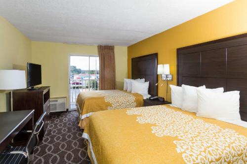 a hotel room with two beds and a flat screen tv at Days Inn & Suites by Wyndham Port Richey in Port Richey