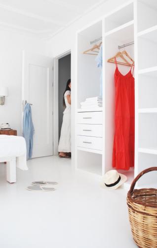 a bedroom with white walls and a closet with red dresses at Casa Montzo boutique hotel in Katelios