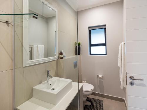 a white bathroom with a sink and a toilet at The Greens Guest House in Knysna