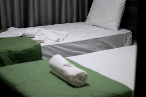 two beds with green and white sheets and a white pillow at Luz Hotel in Goiânia