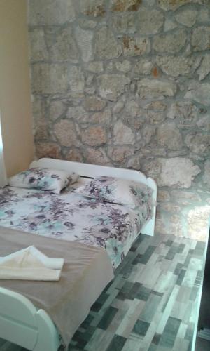 een slaapkamer met een stenen muur en een bed bij Apartment Nada in Rogoznica