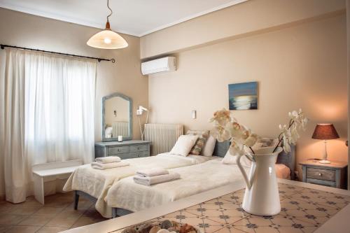a bedroom with two beds and a table with a vase of flowers at Philoxenia Anemomilos in Andros