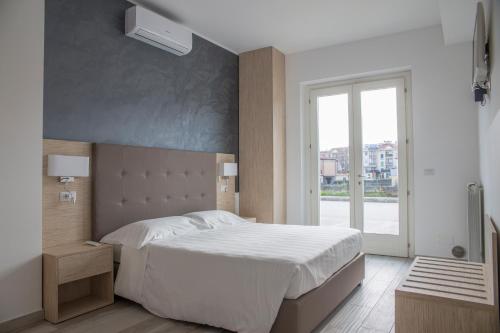 sypialnia z dużym białym łóżkiem i oknem w obiekcie Rooms A due Passi dal Mare w mieście Porto Recanati