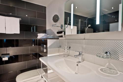 a bathroom with a white sink and a toilet at Wyndham Duisburger Hof in Duisburg
