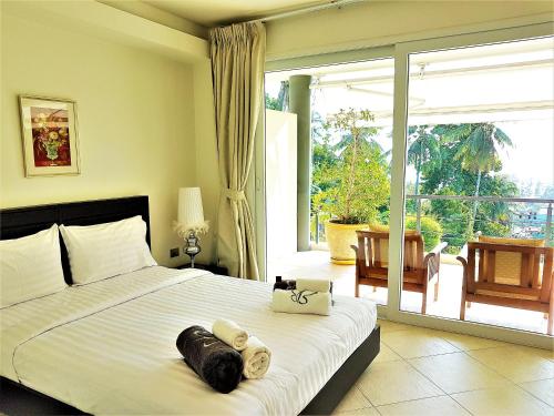 a bedroom with a bed and a large window at KB Apartments Karon Beach by PHR in Karon Beach