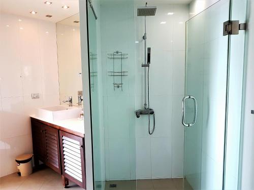 a bathroom with a glass shower and a sink at KB Apartments Karon Beach by PHR in Karon Beach