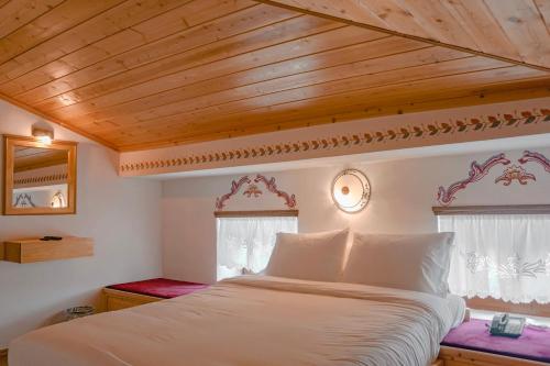 a bedroom with a white bed with a wooden ceiling at Hotel Argjiro in Gjirokastër