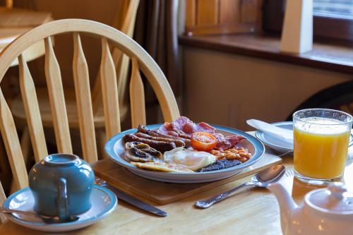 ein Frühstücksteller auf einem Tisch mit Orangensaft in der Unterkunft Neptunes Rest Guest Hotel in Stranraer