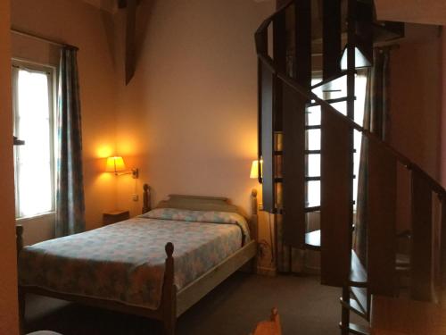 a bedroom with a bed and a spiral staircase at La Fleur de Lys in Cormatin