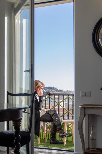 a man sitting on a chair on a balcony at Eleventh Floor Suites in Cagliari