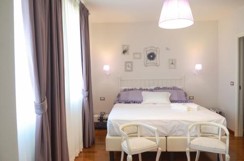 Un dormitorio con una cama blanca con dos sillas. en Villa Montenero, en Cavalcaselle
