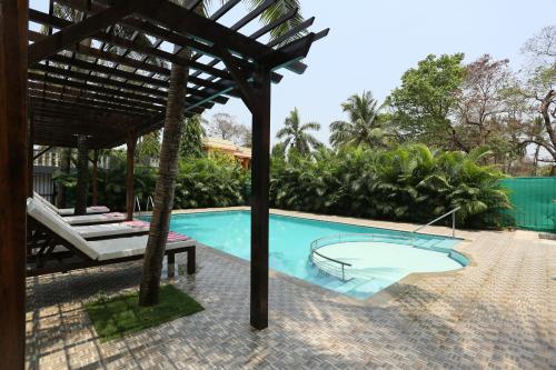 a swimming pool with a pergola next to a house at Motel La Grandeur in Mapusa