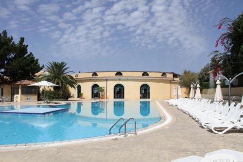 a large swimming pool with white chairs and a building at Green Garden Club in Briatico