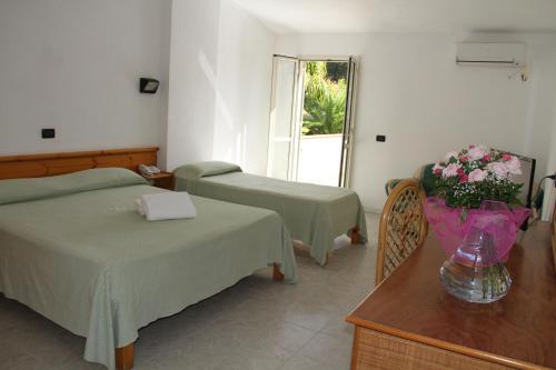een slaapkamer met 2 bedden en een tafel met bloemen erop bij Green Garden Club in Briatico