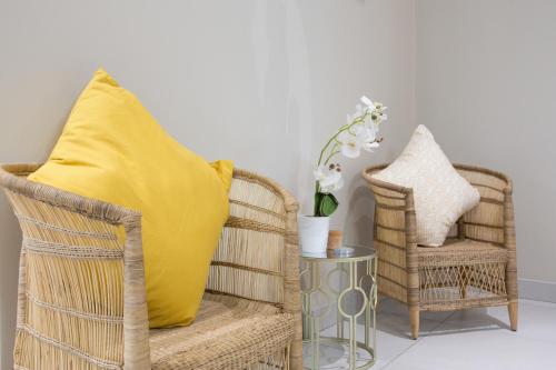 two wicker chairs with a yellow pillow and a table at The Living Collective - The Gates in Hilton