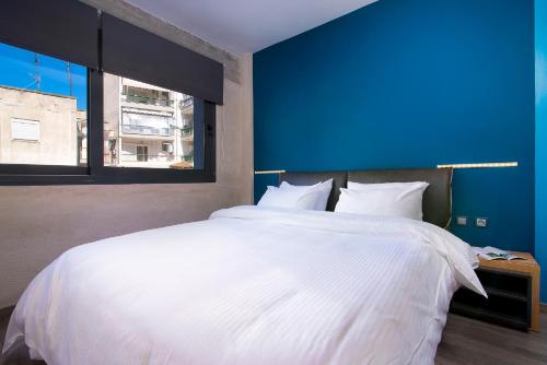 a bedroom with a large white bed with a blue wall at Urban Donkey in Thessaloniki