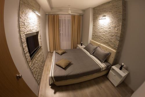 a bedroom with a bed and a tv on a brick wall at Diva Lux Apartman in Belgrade