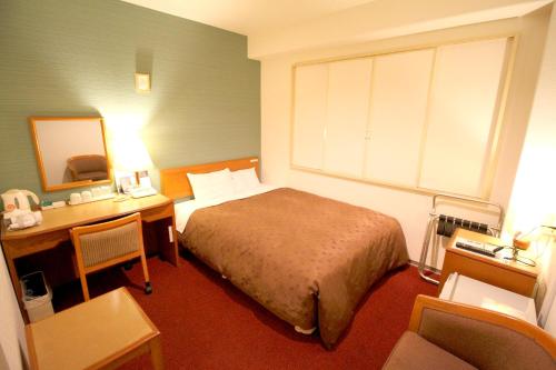 a bedroom with a bed and a desk with a mirror at Smile Hotel Tokyo Shinkoiwa in Tokyo