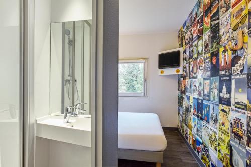 a bathroom with a bed and a sink and a mirror at hotelF1 Toulouse Aéroport in Blagnac