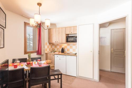 a kitchen and dining room with a table and chairs at Résidence Pierre & Vacances l'Albane in Vars