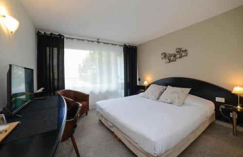 een slaapkamer met een bed, een bureau en een televisie bij Novalaise Plage in Novalaise