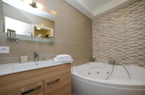 a bathroom with a tub and a sink and a mirror at Novalaise Plage in Novalaise