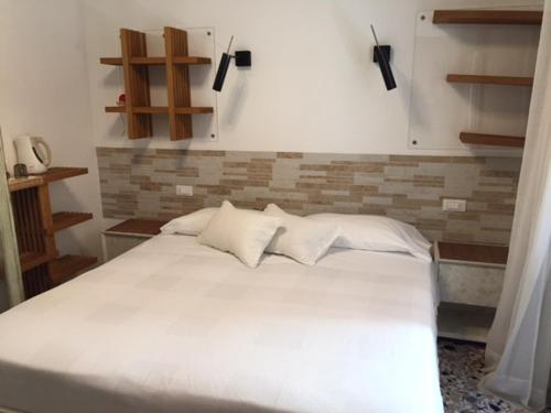 un letto con lenzuola e cuscini bianchi in una stanza di 3C B&B a Venezia