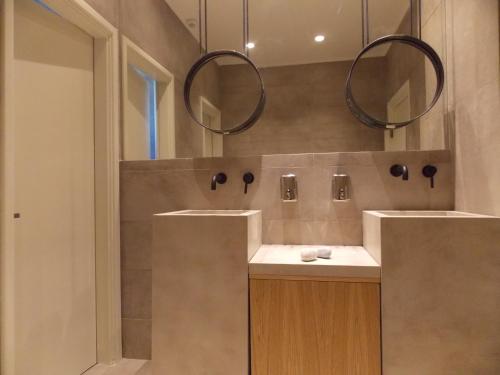 a bathroom with two sinks and two mirrors at Skiros Palace Hotel in Skiros