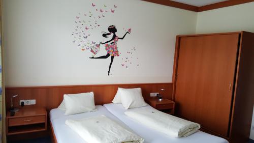 a bedroom with two beds and a painting of a woman on the wall at Gastehaus Melcher in Villach