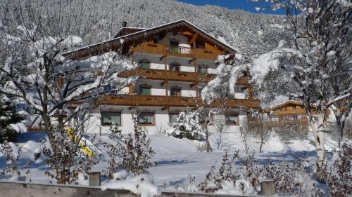 a building covered in snow with trees in front of it at Villa Gemmy in Pozza di Fassa