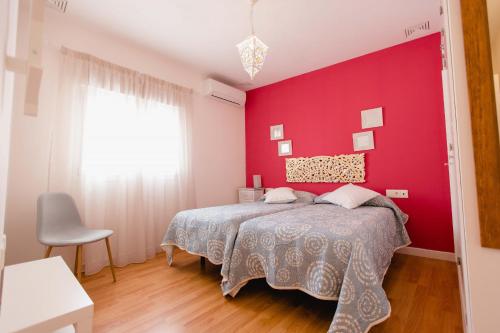 カディスにあるAtico Centro Historicoの赤い壁のベッドルーム1室、ベッド1台が備わります。