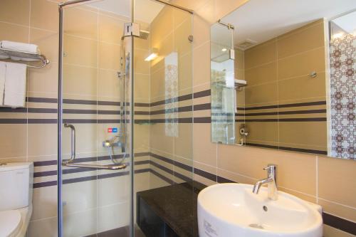 ein Bad mit einem Waschbecken und einer Dusche in der Unterkunft Ngoc Linh Luxury Hotel in Vũng Tàu