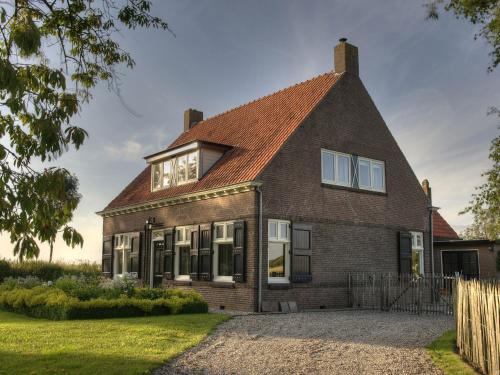 a brick house with a red roof at Spacious Farmhouse in IJzendijke with Garden in Schoondijke