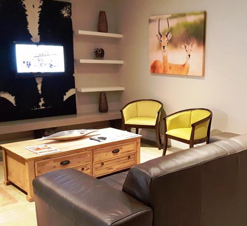 a living room with a couch and two chairs and a tv at Premier Resort Mpongo Private Game Reserve in Macleantown