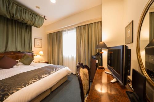 a hotel room with a bed and a flat screen tv at Dukes Hotel Nakasu in Fukuoka