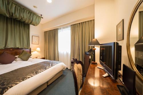 Una habitación de hotel con una cama y un televisor de pantalla plana. en Dukes Hotel Nakasu, en Fukuoka