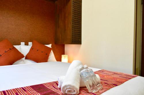 a bed with towels and a bottle of water on it at Mojo Lodge Hakuba in Hakuba