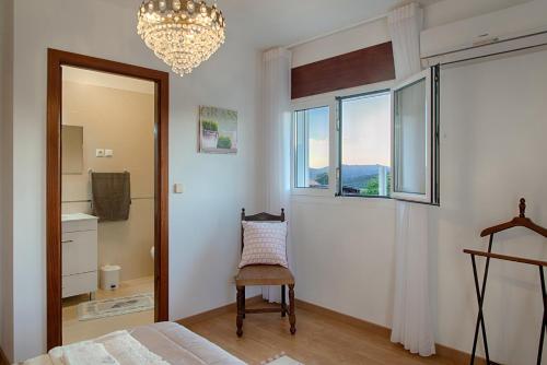 a bedroom with a bed and a chair and a chandelier at Casa Adofreire in Melgaço