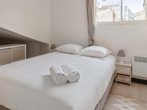 um quarto com uma cama branca e toalhas em Notre Dame Apartment em Bordéus