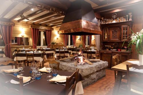 a restaurant with tables and a fireplace in a room at Logis Hotels - Hôtel - Restaurant - Bar - Le Sapin Fleuri in Bourg dʼOueil