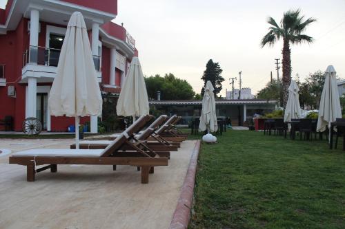 a row of lounges with white umbrellas and chairs at Cilek Butik Hotel in Cesme