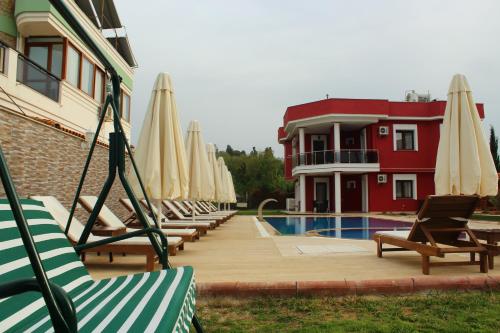 a group of chairs and umbrellas next to a pool at Cilek Butik Hotel in Cesme