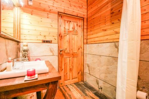 a bathroom with a sink and a wooden wall at Avaas - Bed & Breakfast in Nainital