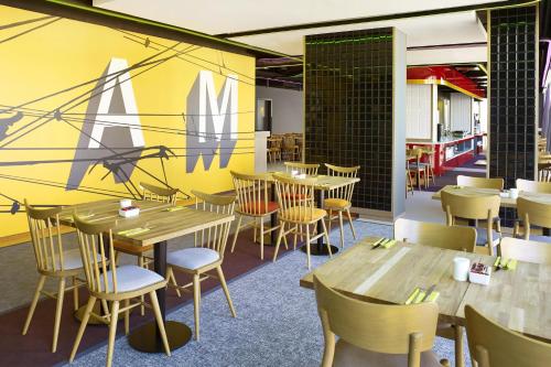 a restaurant with wooden tables and chairs and a yellow wall at ibis Styles Warszawa City in Warsaw