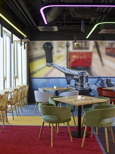 a dining room with tables and chairs and a mural at ibis Styles Warszawa City in Warsaw
