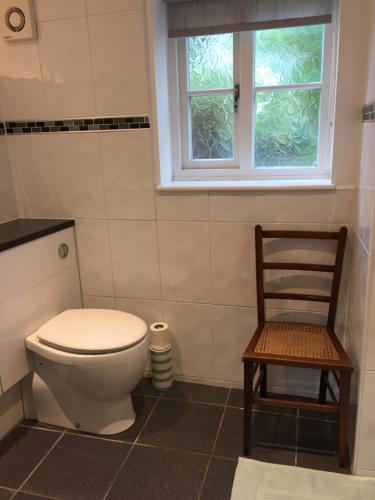 a bathroom with a toilet and a wooden chair at Rock View in Froggatt