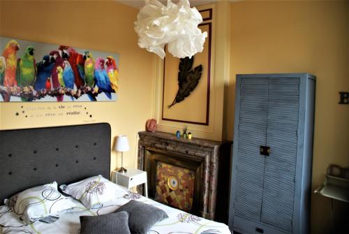 een slaapkamer met een bed en een papegaaienschilderij aan de muur bij Le Clocher in Saint-Julien