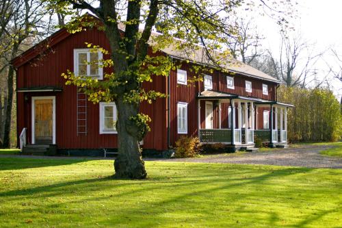 a red house with a tree in front of it at Långshyttans Brukshotell in Långshyttan