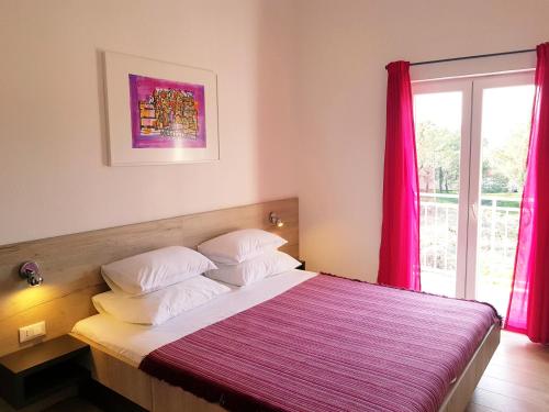 a bedroom with a bed with pink curtains and a window at Apartments Antonio in Cavtat