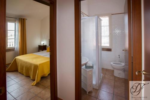 Un dormitorio con una cama y un baño con inodoro. en Tenuta De Fanti Agriturismo, en Bibbona
